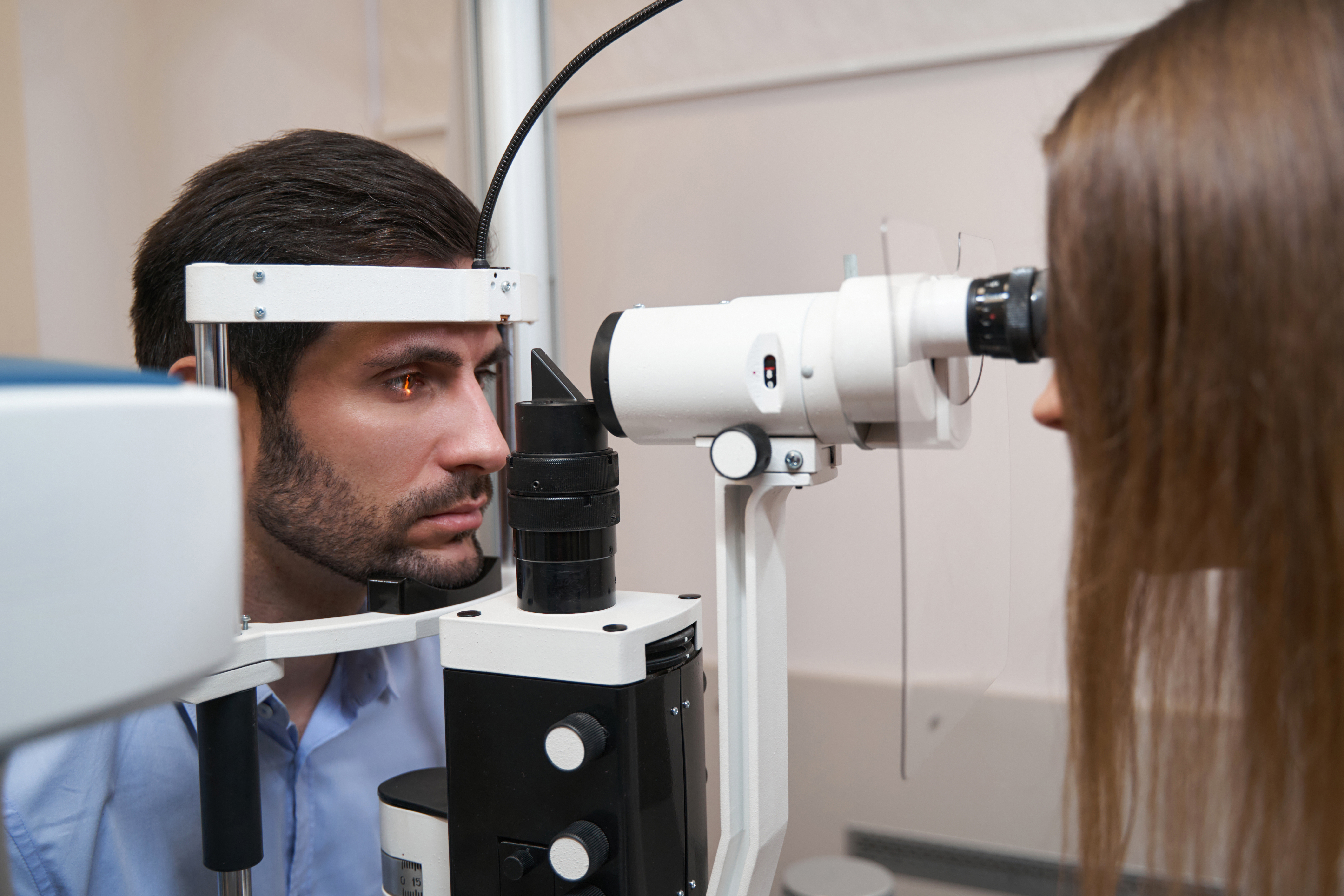 Optometrist shining into patient eye with slit lamp